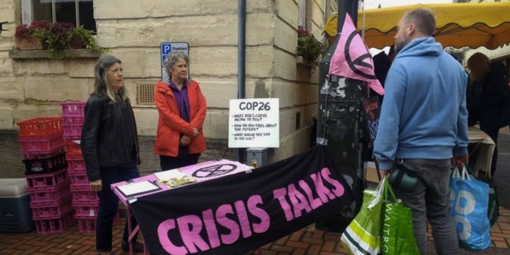 Two rebels talk to a shopper behind a pink crisis talk table.